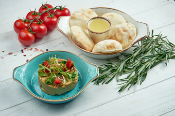 Classic oriental appetizer - chickpea hummus with greens and arugula, pita in a blue plate on a wooden background