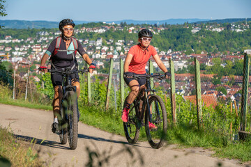 Fototapeta na wymiar Grandmother and granddaughter riding their mountain bikes and having fun on a sunny afternoon in the vineyards above the city of Stuttgart, Baden-Wuerttemberg, Germany