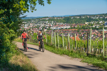 Grandmother and granddaughter riding their mountain bikes and having fun on a sunny afternoon in the vineyards above the city of Stuttgart, Baden-Wuerttemberg, Germany