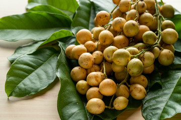 Pile of Burmese Grapes on green leaves at wooden table.
