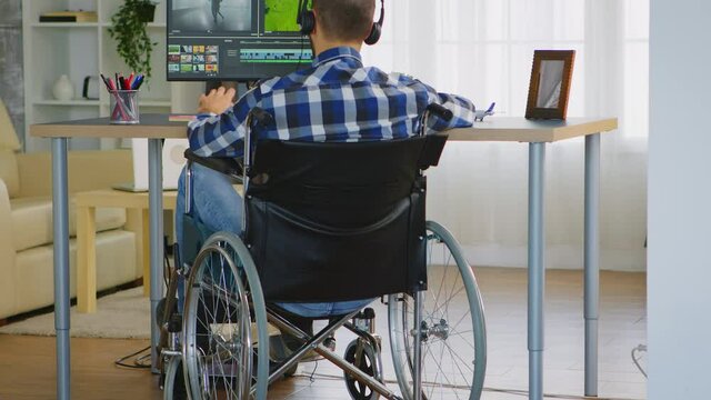 Disabled video editor sitting on wheelchair doing post production on film. Handicapped invalid paralysed freelancer, immobilized entrepreneur working from home, ilness and disability
