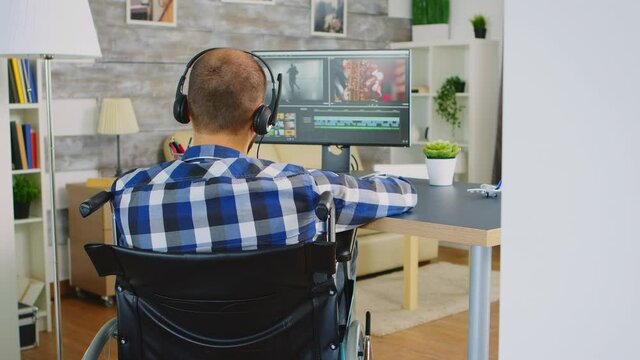 Video editor in wheelchair working on film post production. Handicapped invalid paralysed freelancer, immobilized entrepreneur working from home, ilness and disability