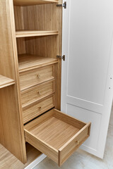 White wardrobe with wooden drawers and shelves. Wooden filling of wardrobe