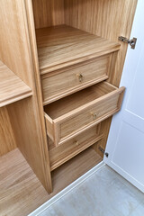 White wardrobe with wooden drawers and shelves. Wooden filling of wardrobe