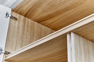 Naklejka na ściany i meble White wardrobe with wooden shelves close-up. Wooden filling of wardrobe