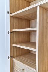 White wardrobe with wooden drawers and shelves. Wooden filling of wardrobe