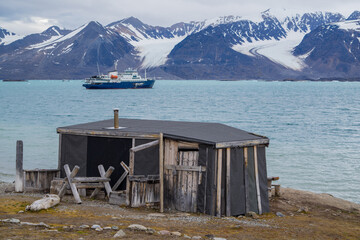 Norway, Spitsbergen, July 7, 2018: Expedition ship in the Arctic summer. A wooden cabin called "Texas Bar" in the foreground.