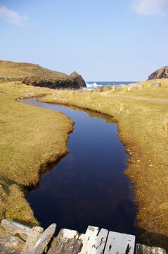 A peaty stream meandering towards Dalbeg Beach on the Isle of Lewis in the Western isles of Scotland.