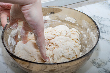 Thick dough is manually mixed in a transparent bowl.