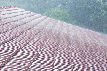 Heavy rain on a red roof in summer