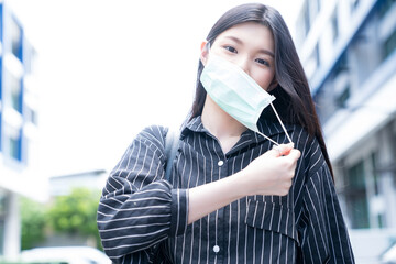 Young Asian girl taking off her face mask during commuting as the situation of Covid-19 pandemic is...