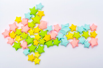 The arrow in the children's style pointing to the left is laid out from multi-colored paper stars. Decor element in layout or scrapbooking.