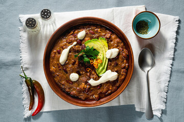 vegan chili soup without meat, with pinto beans and avocado, served with yogurt made from soy on...
