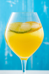 Cold summer delicious coctail with lime and ice in a glass with drops on the white and blue background.