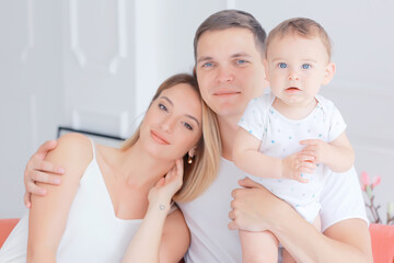 Obraz na płótnie Canvas baby with parents in a cozy house / healthy young family mom dad and baby, happiness smile