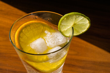 Cold summer delicious coctail with lime and ice in a glass with drops on the wooden  background.