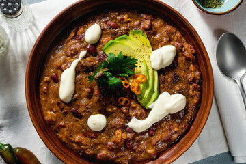 vegan chili soup without meat, with pinto beans and avocado, served with yogurt made from soy on...