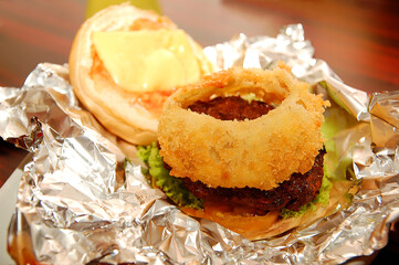 Burger patty with onion ring in bun