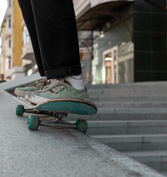 The city walk. A young man in black jeans stands on a skateboard. The photo shows rapid movement. High quality photo