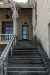 Fototapeta premium An old building with columns and stucco. Wide staircases lead to the second floor. Strict geometry. Summer. High quality photo