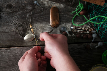 Fisherman is tying a knot on a fishing lure with a metal bait, closeup hands