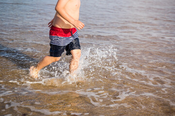 young man running on the beach playing in the water