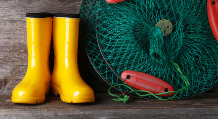Fishing tackle and yellow rubber boots on a wooden vintage background