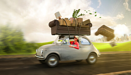 Fototapeta Umzug - Frau im Kleinwagen transportiert Sofa und Hausrat auf ihrem Dach obraz
