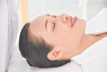 Fototapeta na wymiar Beautiful asian woman receiving facial acupuncture treatment at clinic ,Alternative medicine concept.