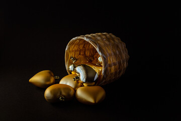 cesta de mimbre con corazones dorados y plateados sobre fondo negro