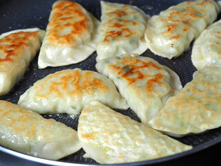Dumplings are fried in a pan. Asian dish with a variety of fillings. Fried Gyoza