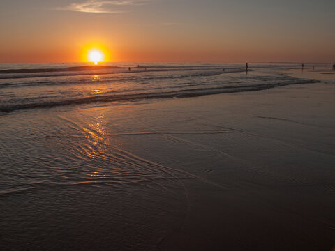 Sunset with reflections in the sand at Zahora beach in summer, Cadiz, Andalusia, Spain
