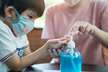 Young mother squeezing hand sanitizer onto little son's hand to prevent the spread of viruses