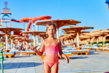 Funny little girl in swimsuit cooling in shower outside - Powered by Adobe