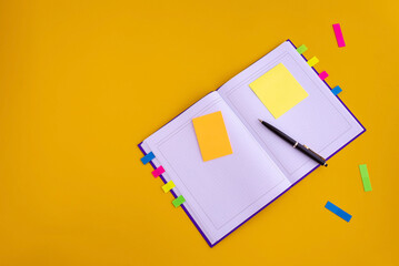 notebook, pen, colored paper for notes, colored stickers on a yellow background