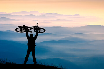 Cyclist who hold bicycle above the head - 357580896