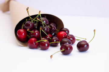 Obraz na płótnie Canvas ripe cherries in a paper bag on a white background, summer harvest