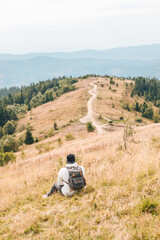 man with backpack hiking by autumn mountains