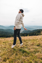 Fototapeta premium man with backpack happy jumping on the peak on the mount