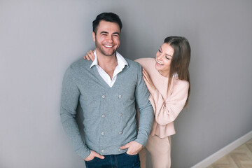 Cheerful young couple standing on grey background.