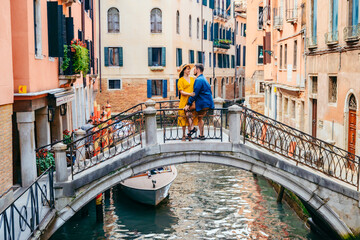 couple standing on the bridge crossing venice canals