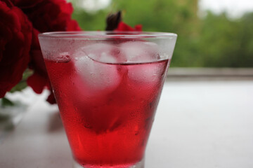 Cold hibiscus tea with ice cubes in the glass. Refreshing non-alcoholic summer drink