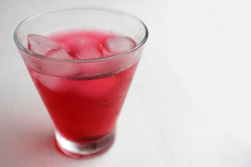 Cold hibiscus tea with ice cubes in the glass. Refreshing non-alcoholic summer drink