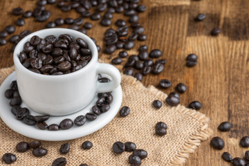 Top view of cup with coffee beans, on wooden table, horizontal, with copy space