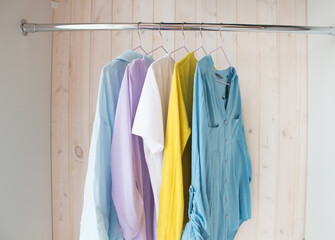clothes of pastel shades on hangers. analysis of the wardrobe