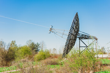 A large radio antenna in the form of a dish stands in the field. Astronomical Observatory of the...