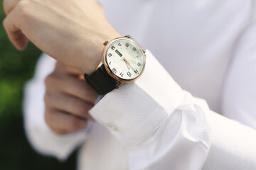 Close-up hands of the groom  with a clock