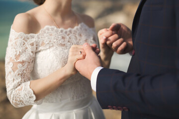 Obraz na płótnie Canvas Bride and groom hold hands during the wedding ceremony