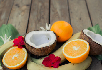 Tropical fruit on the wooden background. Fruits background. Coconut, oranges and bananas on a wooden table.