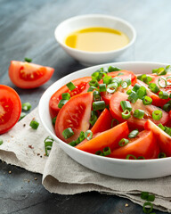 Tomato salad with spring onion and herbs in white bowl. Healthy summer food